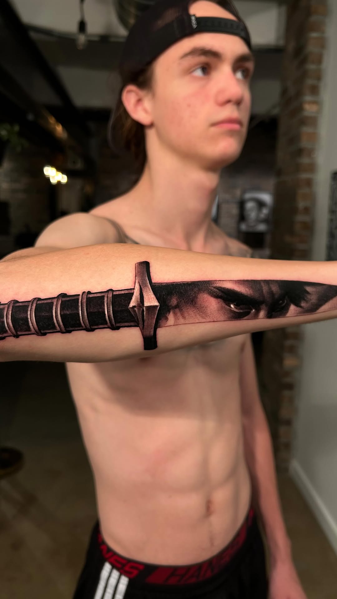 Black-and-grey sword tattoo on forearm