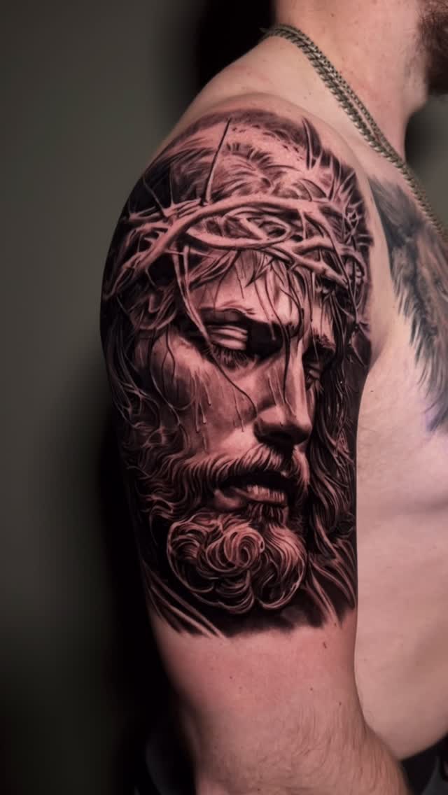 Jesus portrait tattoo, black-and-grey shoulder