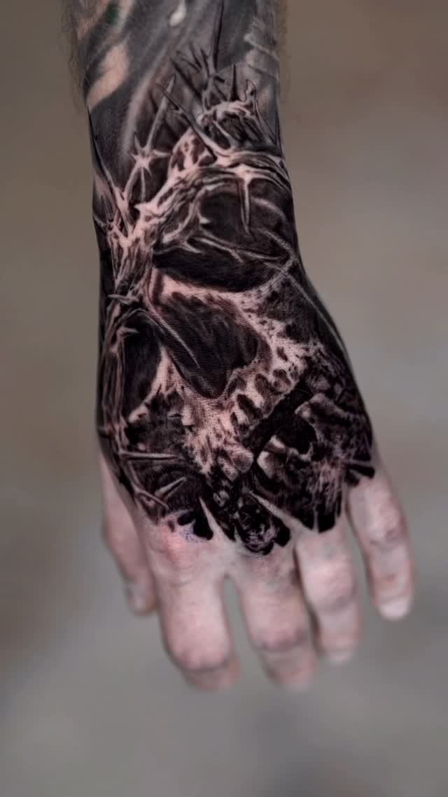 Black-and-grey skull hand tattoo with tree branches