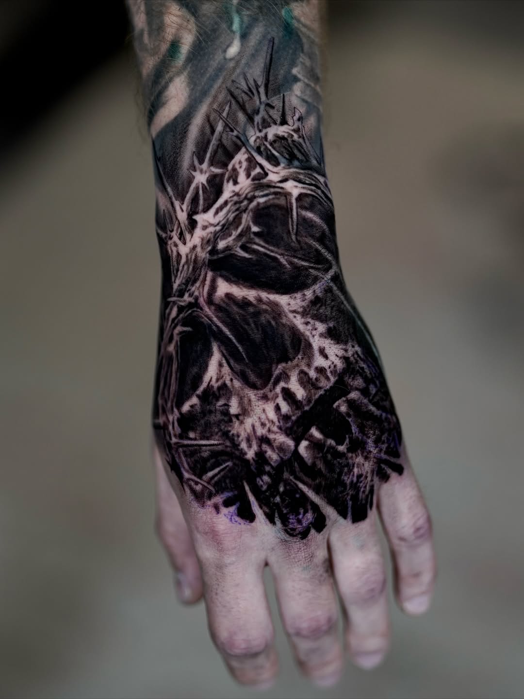 Black-and-grey skull hand tattoo with raven