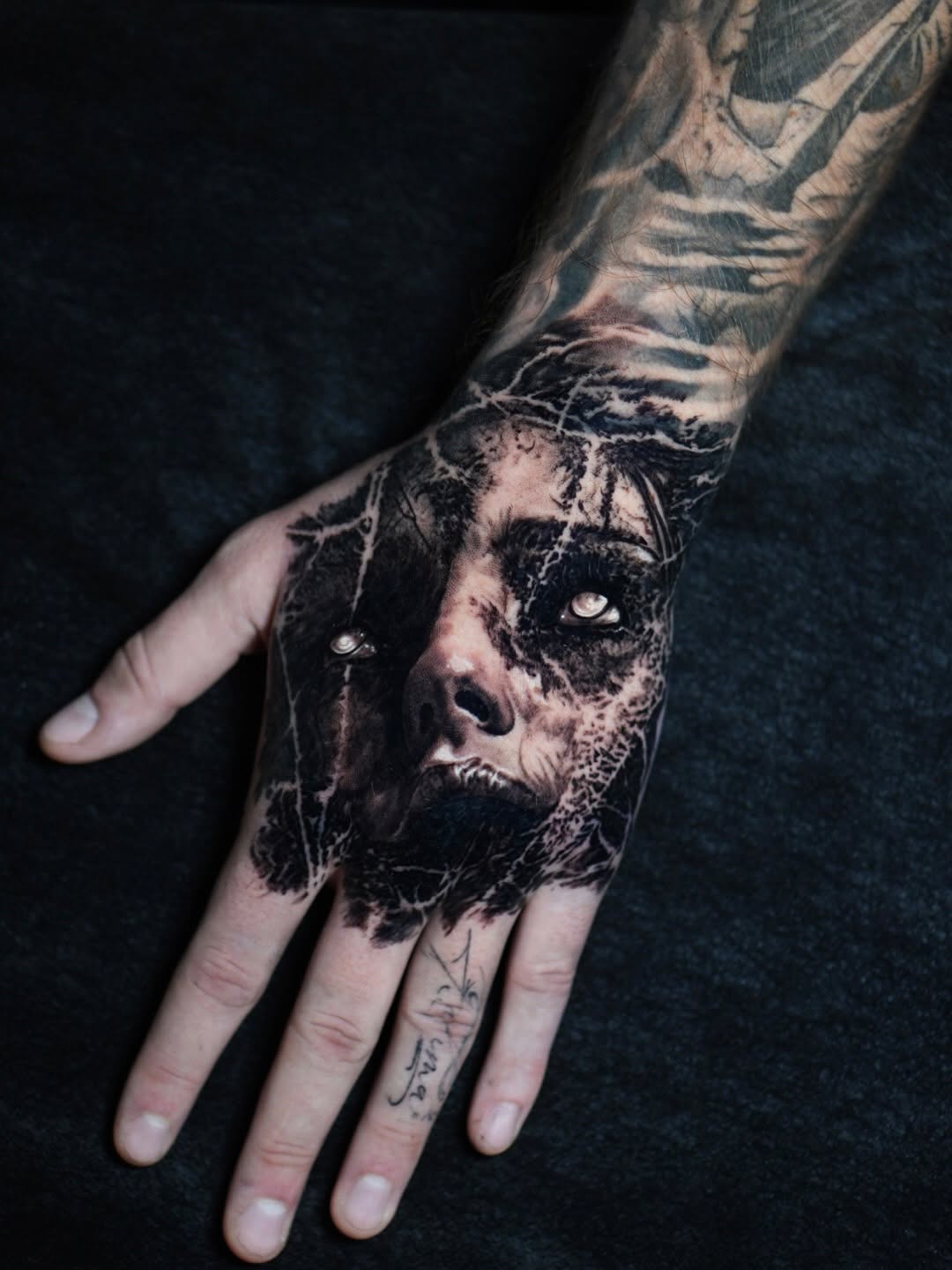 Black-and-grey portrait demon hand tattoo