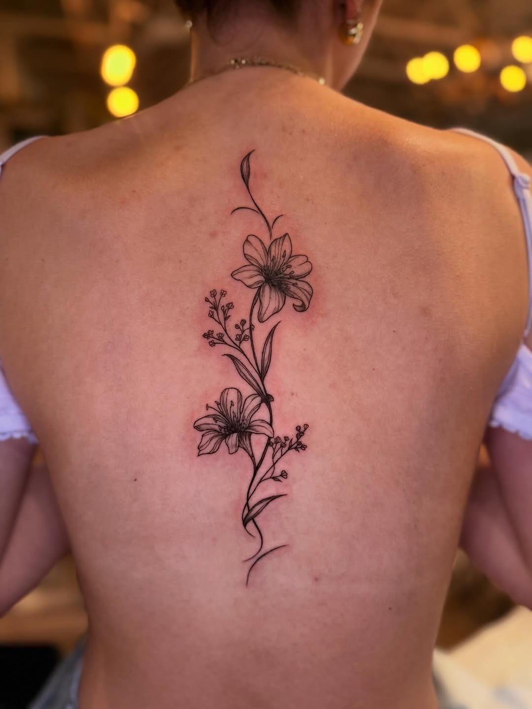 Floral spine tattoo with fine-line flowers