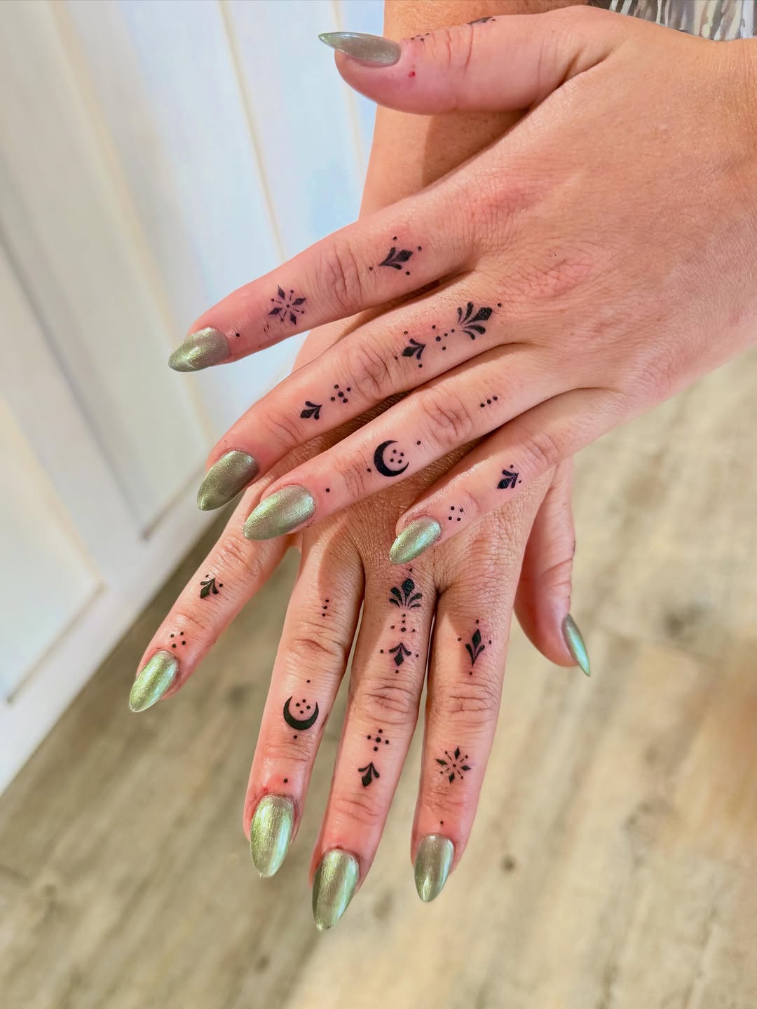 Fine-line ornamental finger tattoos with celestial motifs