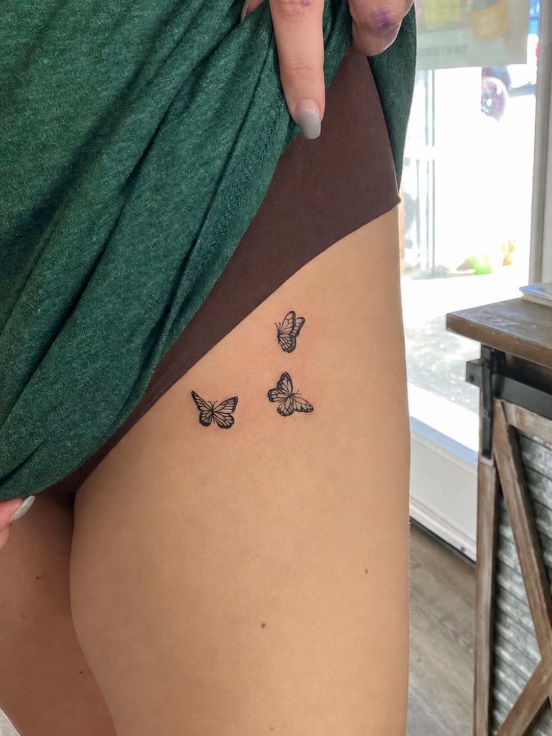 Fine-line butterfly trio thigh tattoo