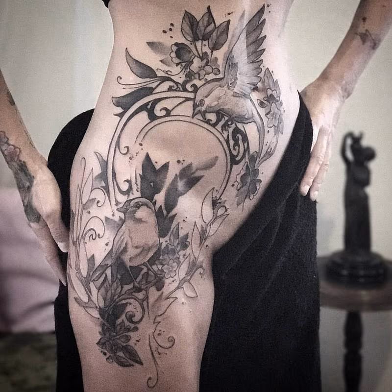 Birds, flowers, vines with Art Nouveau filigree on model's hip. Black and grey.